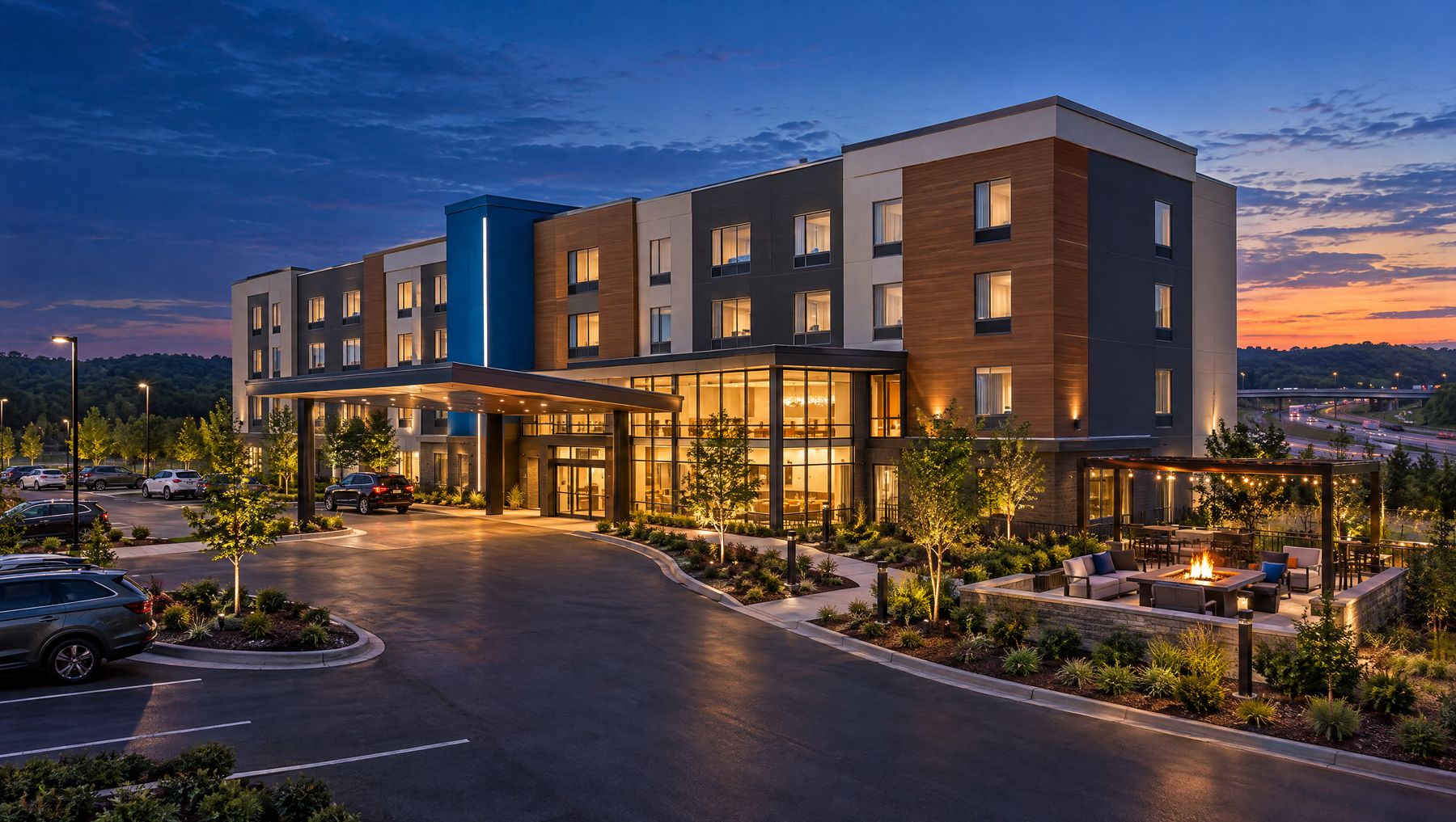 Concept rendering of a four-story select-service hotel with a glowing lobby and porte-cochere at dusk
